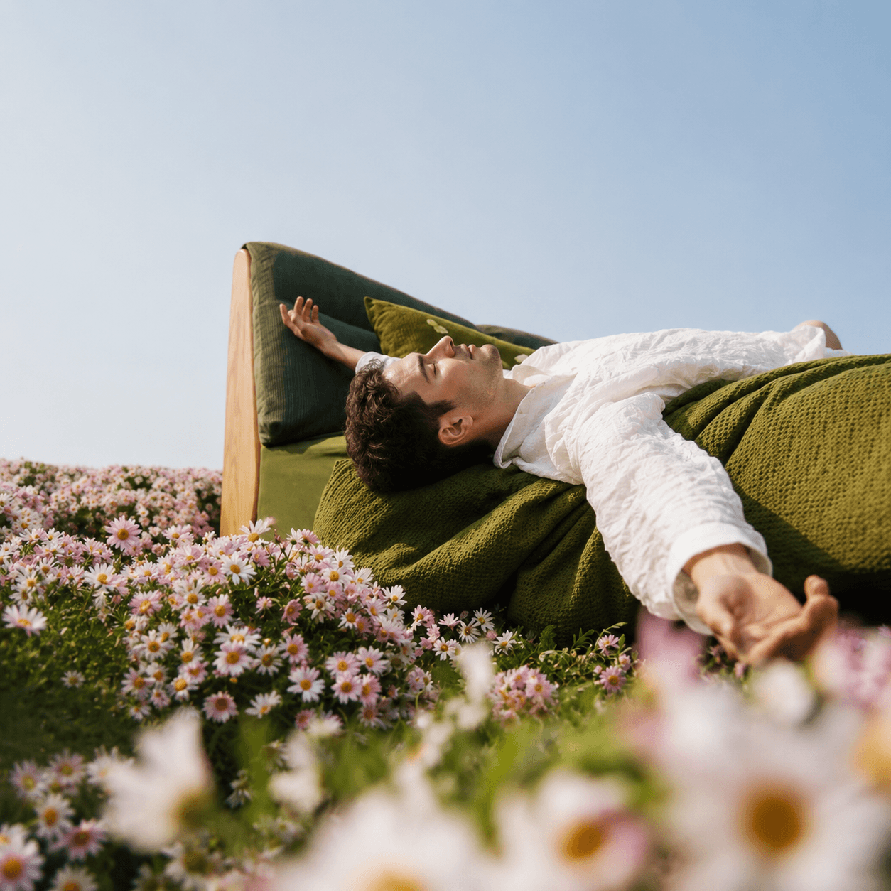 A young man on a couch amidst a wildflower meadow, symbolizing convenience of online medical care.